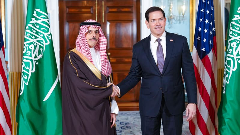 Saudi Foreign Minister Faisal bin Farhan shakes hands with US Secretary of State Marco Rubio between Saudi and US flags