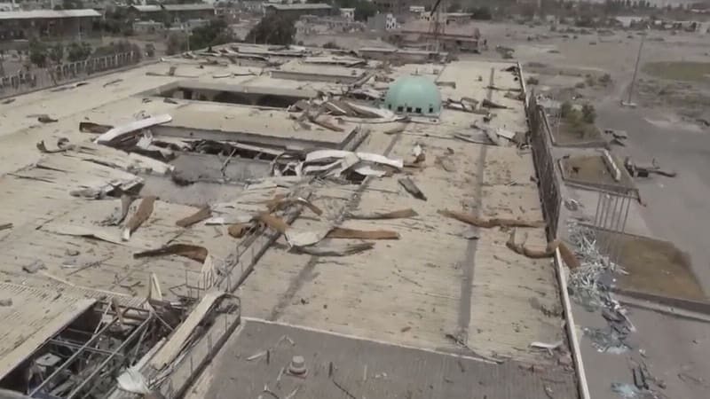 Aerial view of the damaged terminal roof at Aden International Airport in Yemen, with a green dome beyond
