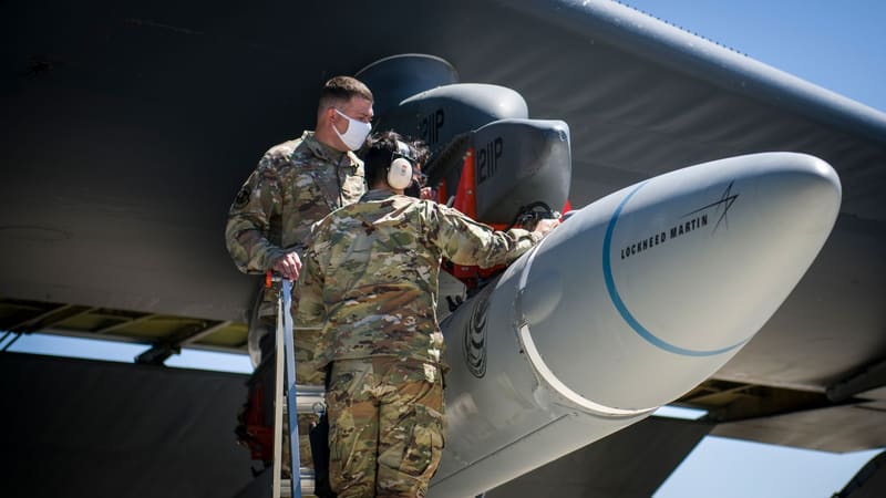 Two airmen secure the nose of an ARRW prototype bearing the Lockheed Martin logo under a B-52H wing