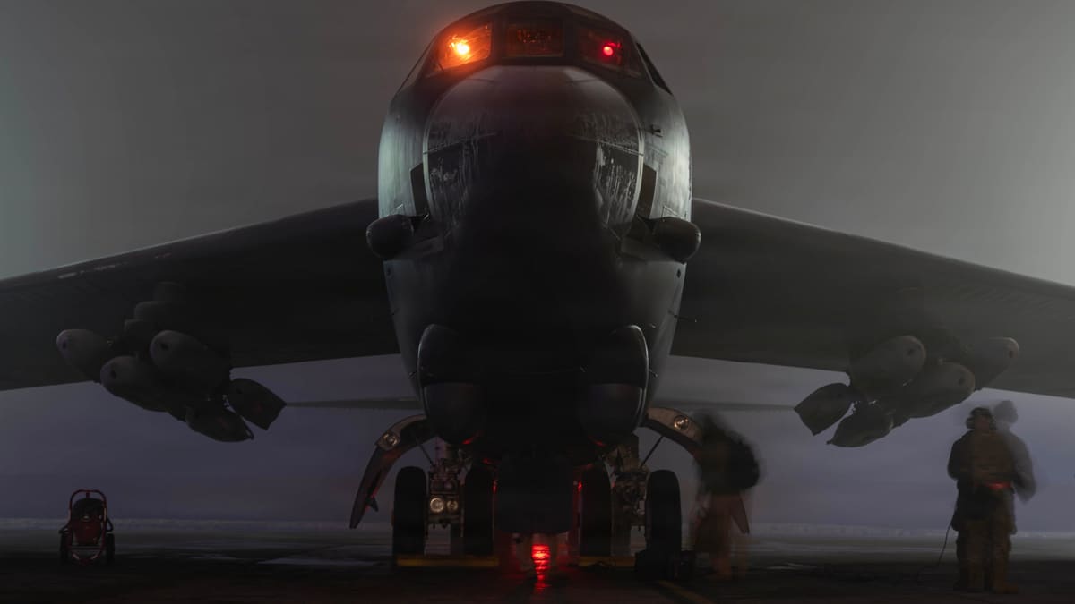 US Air Force B-52H Stratofortress seen head-on at night with AGM-158 JASSM missiles on its wing pylons as crew board