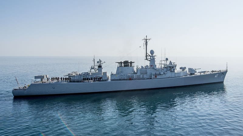 A grey Bulgarian Navy frigate with hull number 42 on a calm Black Sea, sailors lined up on deck.