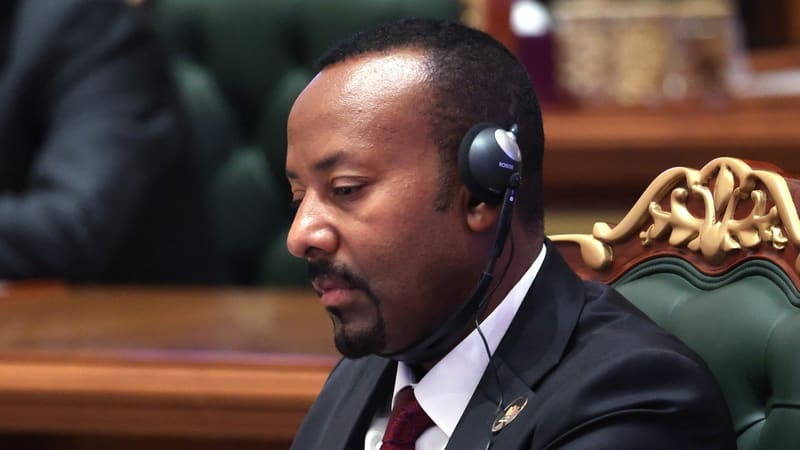 Ethiopian Prime Minister Abiy Ahmed in a dark suit and interpretation headset looks down at a summit table