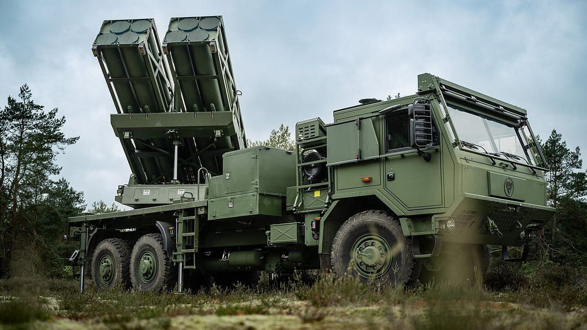 A green Dutch PULS launcher truck with two raised launch pods, each with four sealed launch cells, on heathland