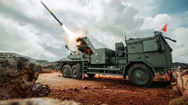 A Dutch PULS rocket launcher on a six-wheel truck fires a rocket from its pod on a rocky hillside on Crete