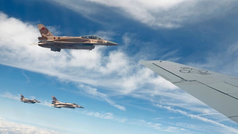Three Royal Moroccan Air Force F-16s in desert camouflage fly beside the wing of a US Air Force KC-135 tanker over Morocco