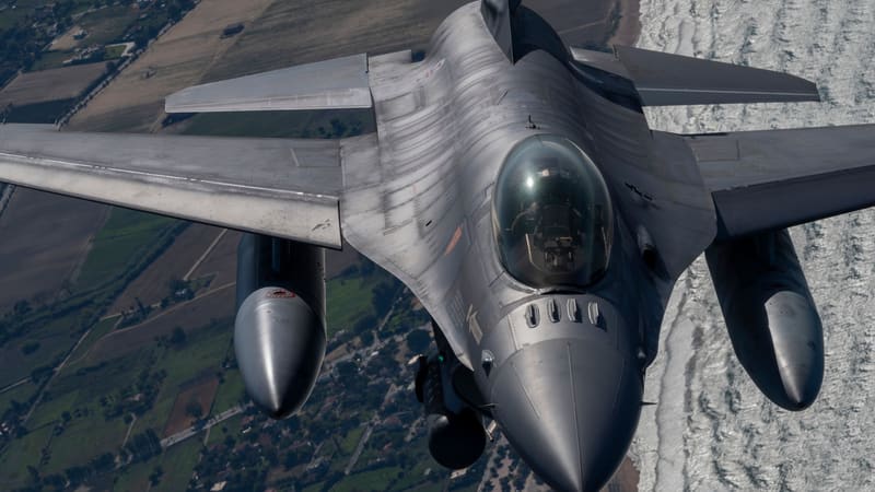Portuguese Air Force F-16 fighter seen head-on in flight, with two external fuel tanks, over farmland and coastline