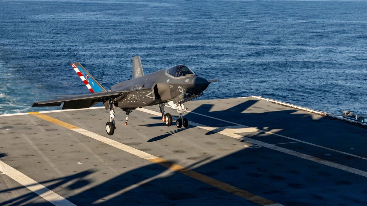 F-35C stealth fighter with landing gear down, moments above an aircraft carrier flight deck over open sea