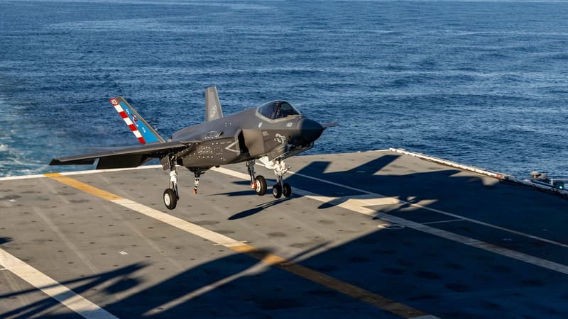 F-35C stealth fighter with landing gear down, moments above an aircraft carrier flight deck over open sea
