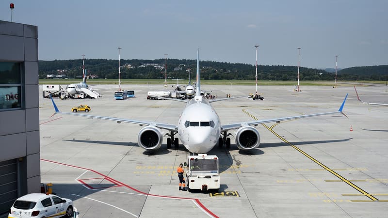 Front view of a flydubai Boeing 737 MAX 8 on the apron at Krakow airport, with a tug and a ground worker in front of it
