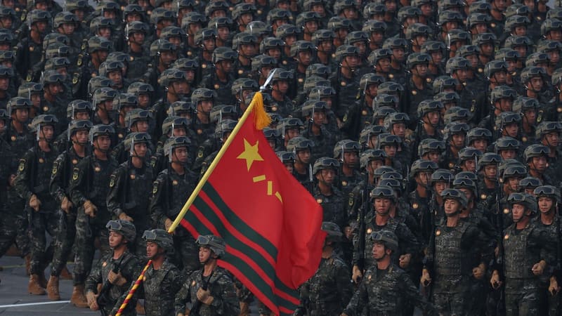 Rows of Chinese paramilitary troops in helmets and goggles march behind a red flag at the 2025 Beijing parade