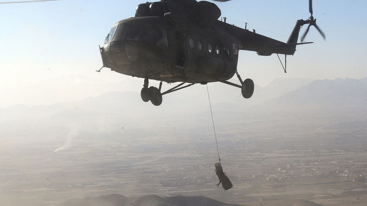 A Polish military helicopter lifts a litter on a rope over hazy terrain in Ghazni province, Afghanistan.