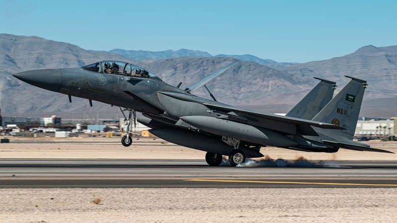 A Royal Saudi Air Force F-15SA fighter touches down on a desert runway with mountains behind it