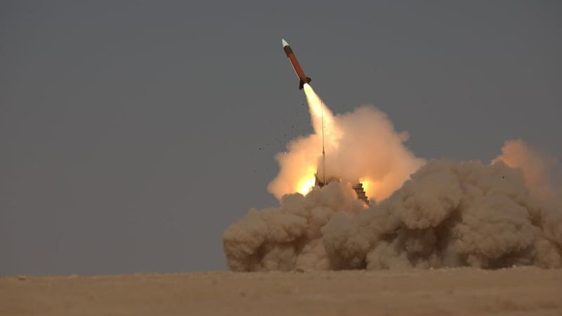 A Patriot interceptor climbs from a launcher in a cloud of dust and smoke over flat desert sand