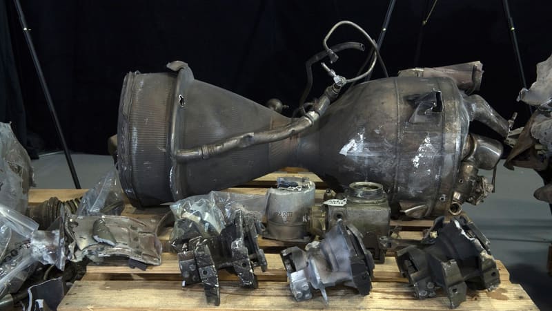 Scorched engine and combustion chamber of a recovered Qiam-class ballistic missile on a wooden pallet with valves and parts
