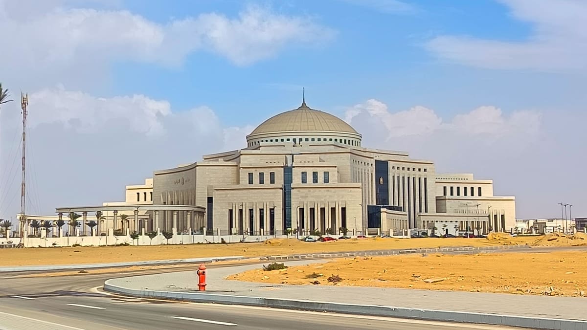 Domed stone House of Representatives building in Egypt's New Administrative Capital across a sandy lot under a blue sky