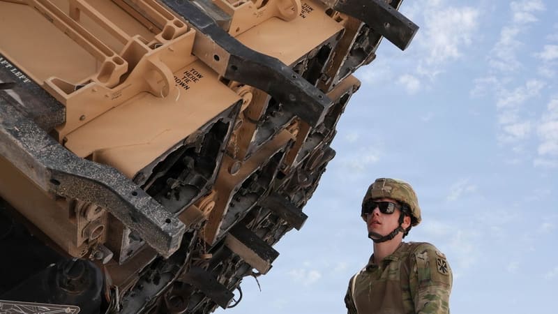 Soldier in helmet and sunglasses beside a tilted Patriot launcher with torn, soot-blackened canister ends