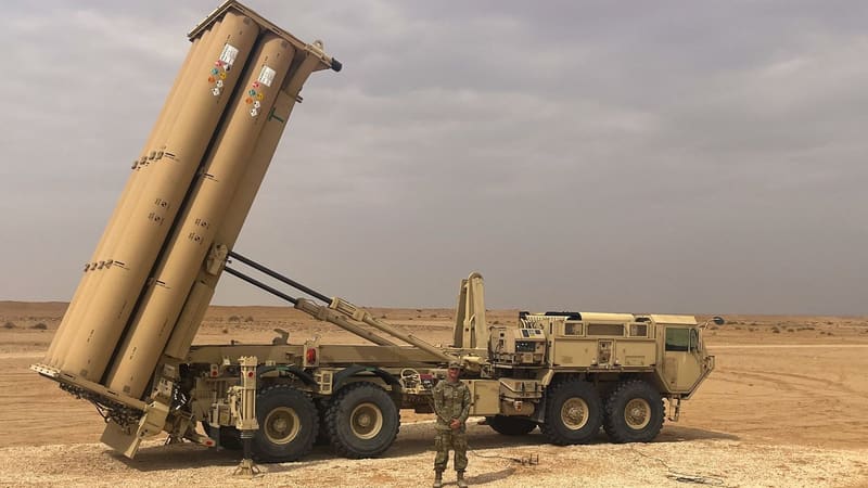 A U.S. soldier stands in front of a THAAD launcher with its rack raised in the desert