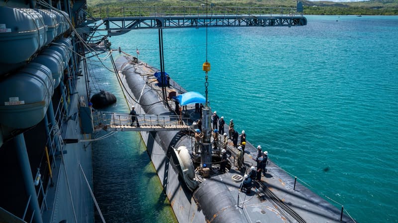 Sailors lower a Tomahawk canister by crane into a missile tube on guided-missile submarine USS Florida in Guam
