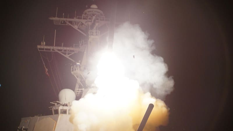 Destroyer USS Stout launches a Tomahawk cruise missile at night in a burst of flame and smoke