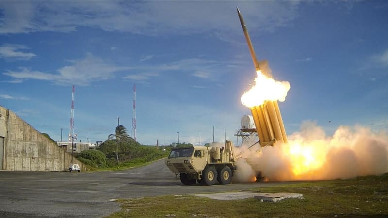 Tan THAAD launcher truck fires an interceptor from one of its canisters in a burst of flame and smoke