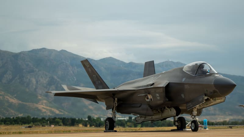 U.S. Air Force F-35A Lightning II stealth fighter with a pilot in the cockpit on a flightline, mountains behind