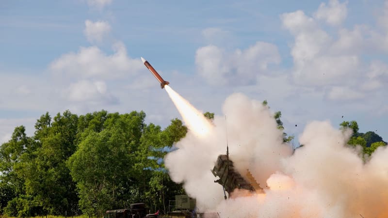 A Patriot interceptor missile climbs from an M903 launcher in a cloud of exhaust smoke beside a tree line