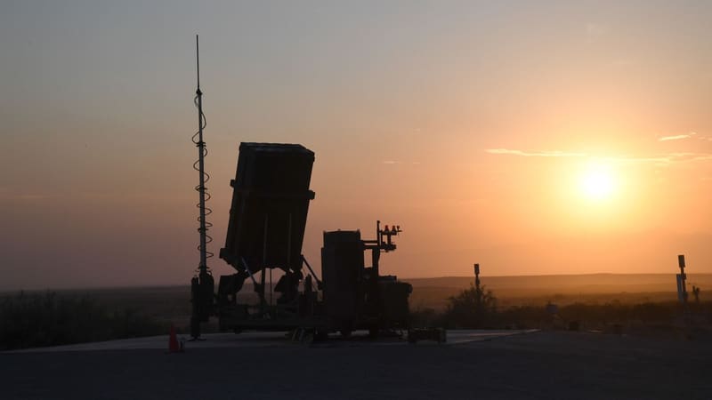 Silhouette of an Iron Dome launcher, its antenna mast and equipment against a sunset sky