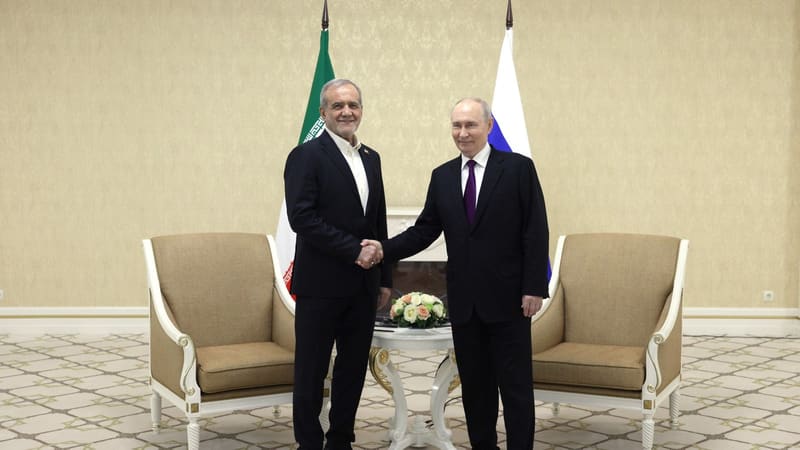 Vladimir Putin and Masoud Pezeshkian shake hands in front of Iranian and Russian flags