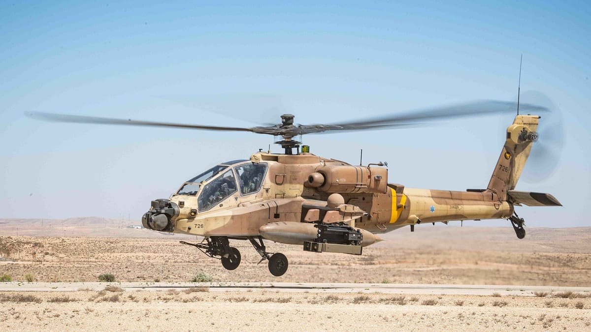 An Israeli Air Force AH-64D Apache in desert camouflage hovering low over a runway with a Spike NLOS launcher