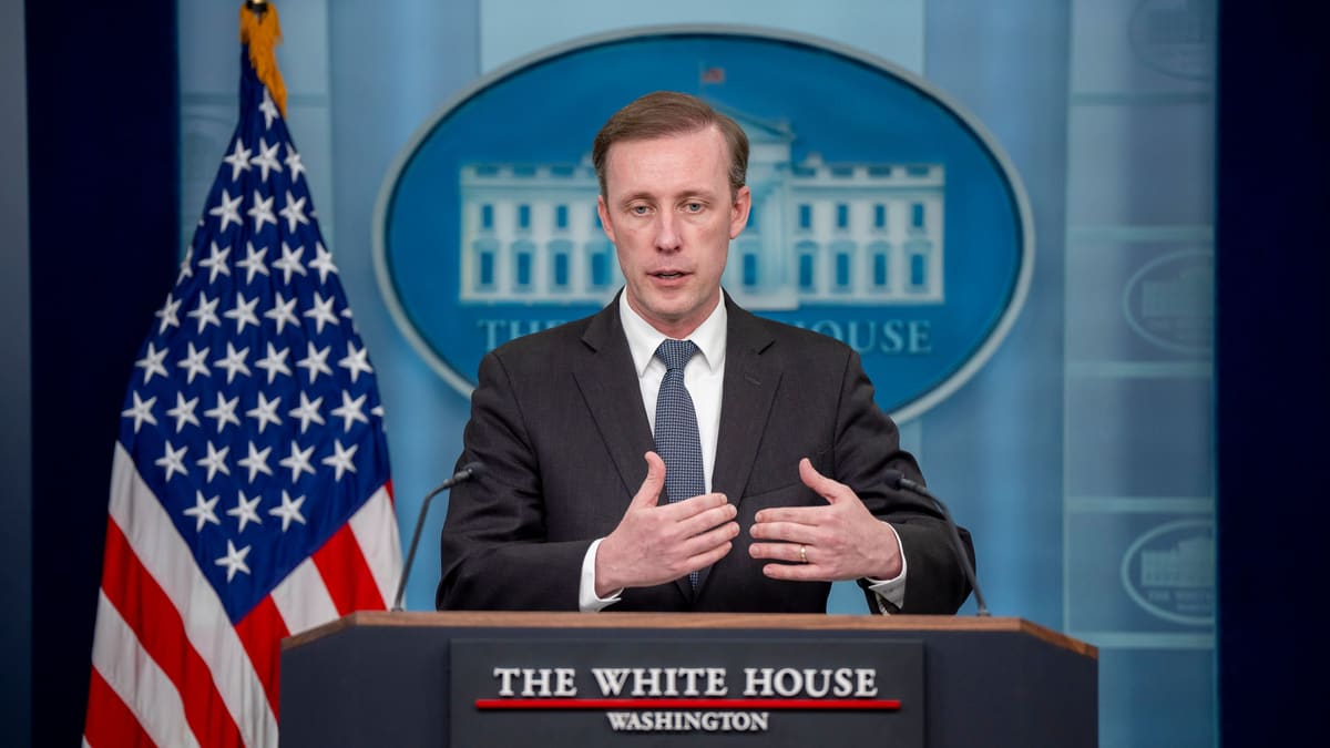 Jake Sullivan speaks at the White House briefing room podium, with a US flag and the White House seal behind him