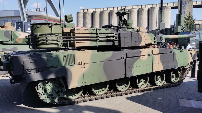 Left side of a camouflaged K2 tank on display, showing the rear hull section that houses the engine