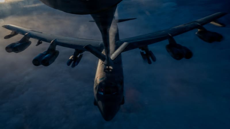 View down a KC-135 tanker's boom to a B-52H bomber flying below it above the clouds.