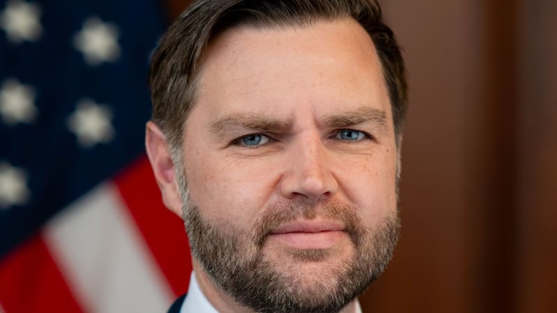 Close-up official portrait of US Vice President JD Vance in front of an American flag