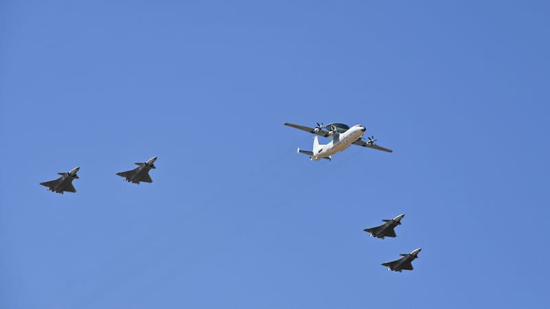 A KJ-500 radar aircraft with a dorsal radome flying in formation with four J-20 stealth fighters