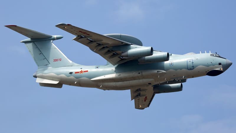 A pale blue KJ-2000 radar aircraft with a large disc radome above its fuselage flying against a blue sky