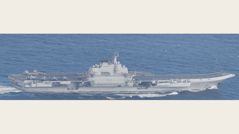 Chinese aircraft carrier Liaoning, hull number 16, sailing in side profile with fighter jets parked on its flight deck