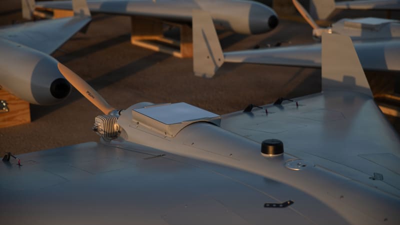 Rear of a LUCAS drone showing its small finned piston engine and wooden pusher propeller, with rows of drones behind