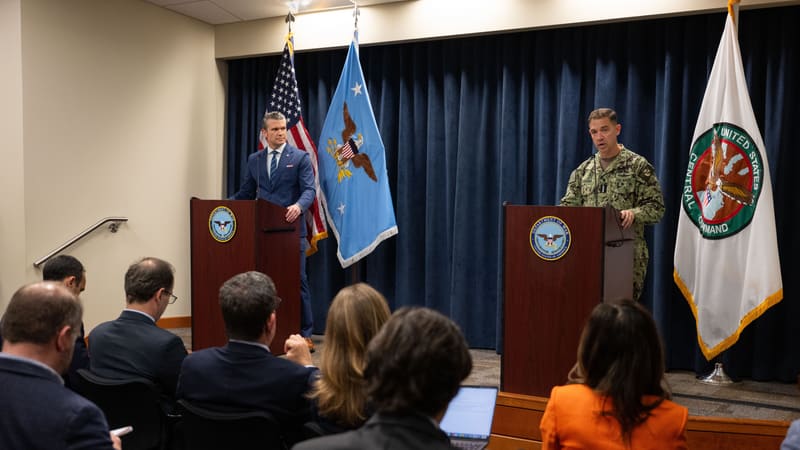Pete Hegseth and Adm. Brad Cooper stand at podiums before reporters at MacDill Air Force Base