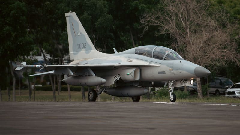 Philippine Air Force FA-50PH jet with serial 002, underwing and centreline fuel tanks, taxiing past trees