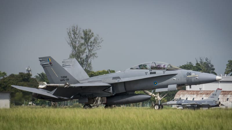Two-seat Royal Malaysian Air Force F/A-18D Hornet with TUDM markings on a runway beside grass