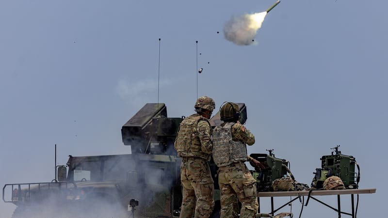 Two U.S. soldiers beside an Avenger vehicle as a Stinger missile leaves its launcher