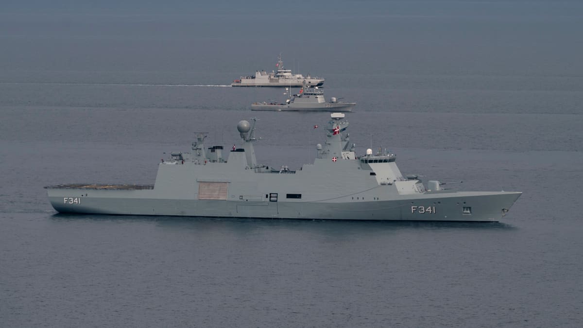 A long grey Danish frigate marked F341 sails on calm water with two smaller warships behind it.