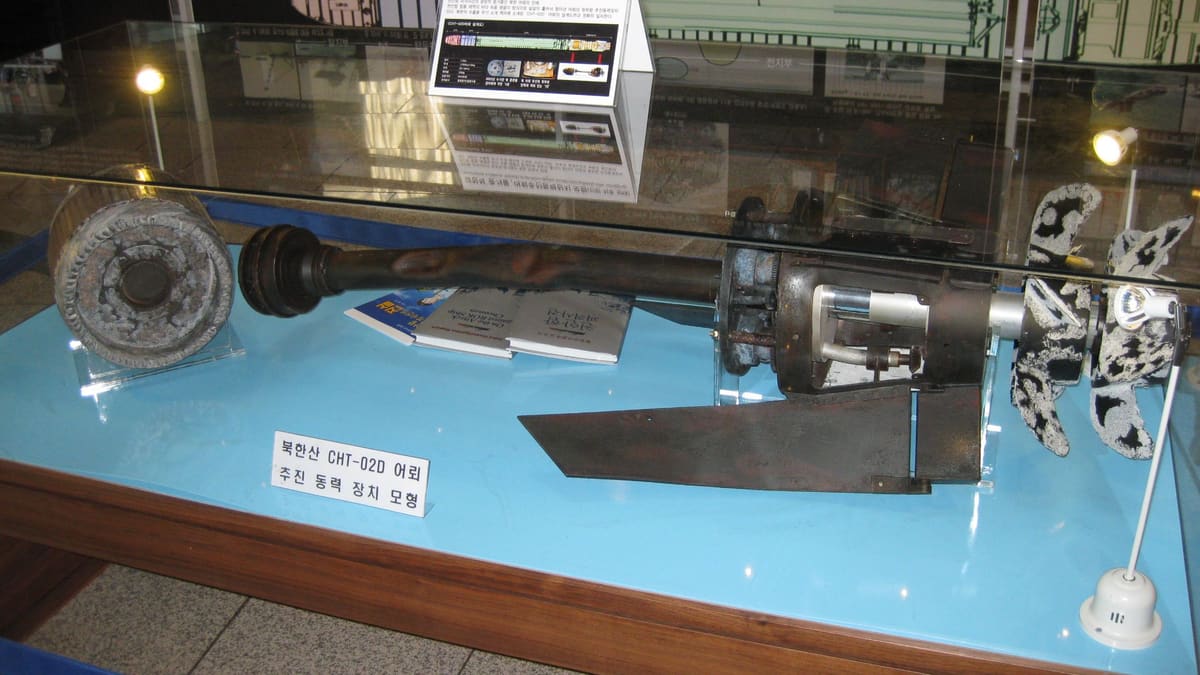 Museum case with a labelled model of a North Korean CHT-02D torpedo propulsion section, shaft and propeller