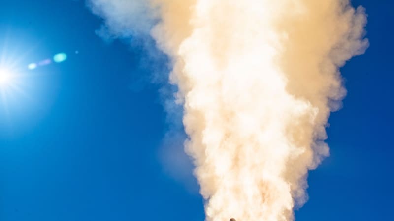 An SM-3 Block IIA interceptor rises from a warship's vertical launcher in a column of smoke against a blue sky