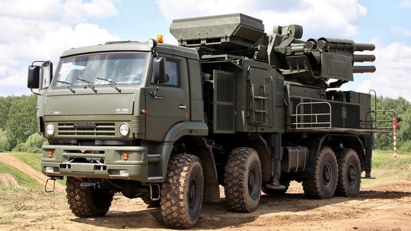 A Pantsir-S1 air defence vehicle on an eight-wheeled KAMAZ truck with its radar and missile tubes on a dirt track