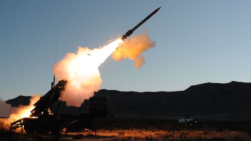 A PAC-3 MSE interceptor climbs from a Patriot launcher in a burst of flame at dusk over a desert range
