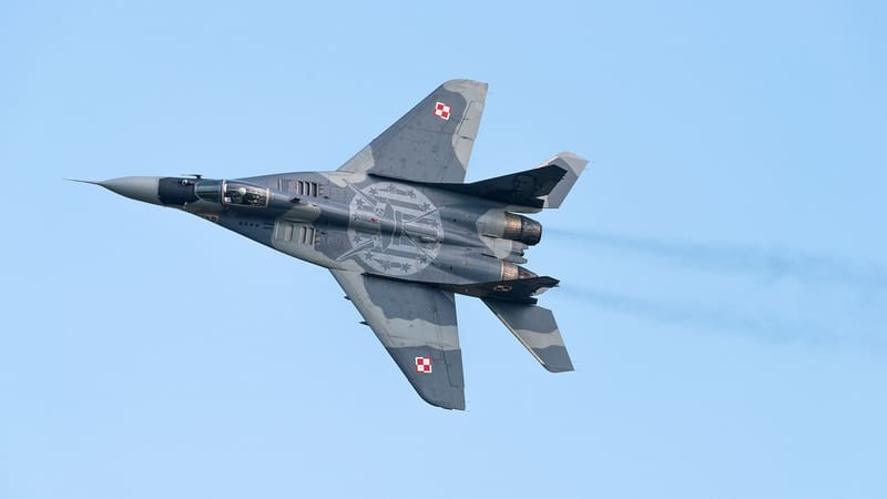 Polish Air Force MiG-29A fighter banking in flight against a blue sky, red and white checkerboard markings on its wings