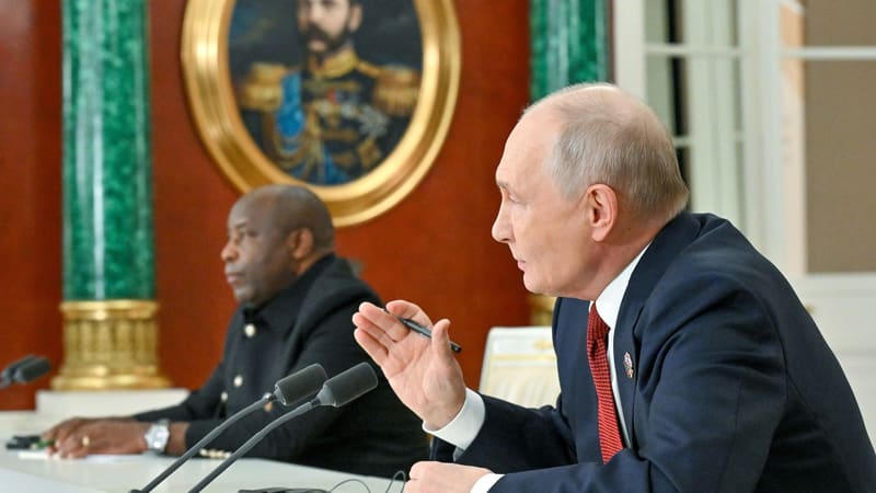 Putin gestures with a pen at the press conference while a second speaker sits beside him
