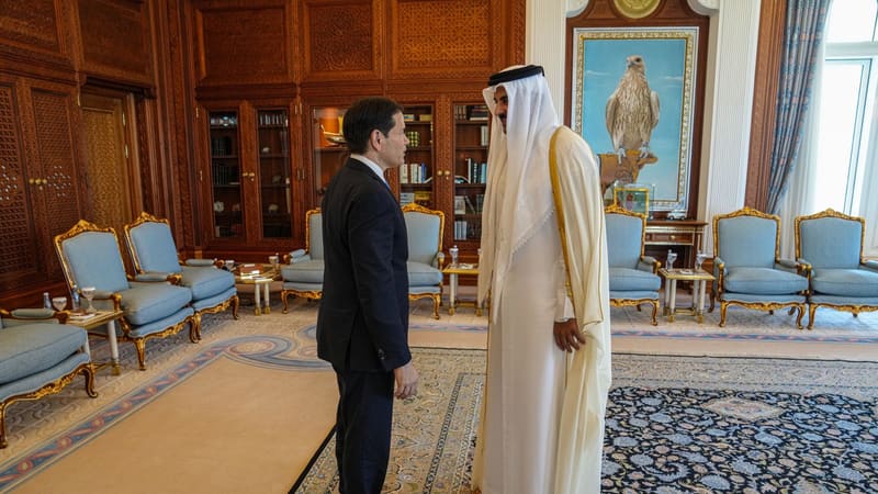 Qatar's emir in white robes faces Marco Rubio in a dark suit in an ornate palace office