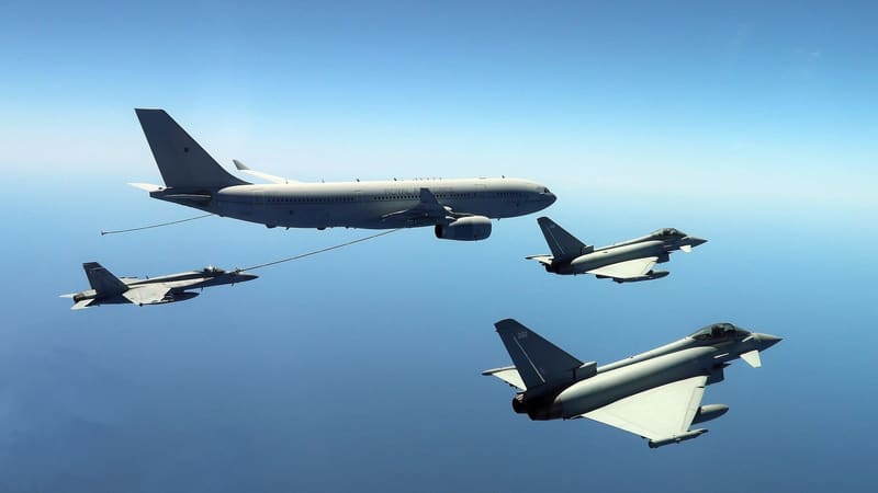 An RAF Voyager tanker refuels a U.S. Navy Super Hornet by hose as two RAF Typhoons fly alongside over the sea